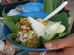 Arroz de lisa (mullet rice) from Barranquilla served in bijao leaf with cooked yuca, a triangle of costeño cheese and a sauce of suero atollabuey.