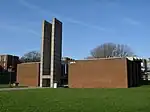 A low red-brick building whose off-centred entrance is dominated by two tall vertical concrete fins