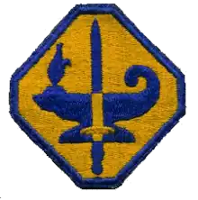 Photograph of the blue and gold octagon-shaped insignia patch for the Army Specialized Training Program (ASTP), featuring an oil lamp and sword at its center