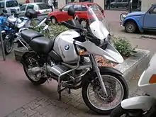 Silver BMW R1150GS parked on a city street with other cars and bikes in the background