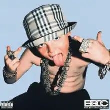 An adolescent boy wearing a bucket hat, neck chain and accessories on his hands sticking out his tongue and with his middle fingers up