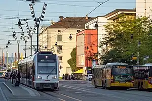 White and red tram and yellow busses