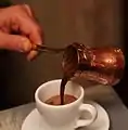 Copper cezve with Turkish coffee pouring out