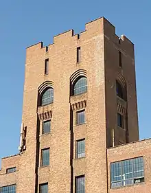 Close-up photo of Lafayette building tower.  Visible are rooftop parapets arched windows with decorative corbels.