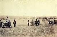 Photograph showing a line of artillery batteries standing at the ready in the foreground with cavalry and other troops massed in the background