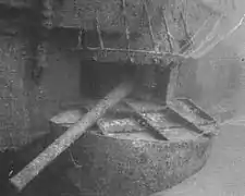 Underwater photograph of a gun protruding from an opening in the side of a sunken ship.