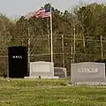 Looking east at multiple tombstones and a flagpole.