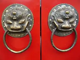 A traditional red Chinese door with Imperial guardian lion knocker resembles the number 8 (good luck or fortune in Chinese culture)