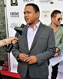 Writer-director Benjamin Bryant is speaking to a journalist on a red carpet at an event