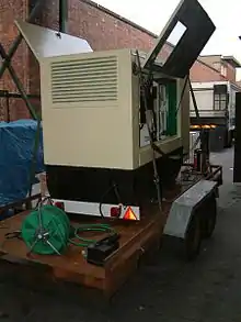 Side view of a skid mounted diesel generator, strapped onto a vehicle trailer.