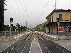 Two-story building with hip roof next to double-track railway line