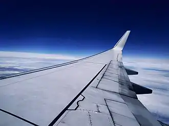 A generic Boeing 737-800 cruising at 32,000 feet. Below it are a pack of clouds. Above it is a vivid, ambient blue sky.