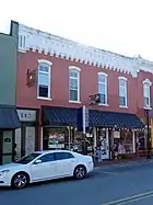 Two-story red brick building with blue overhang over the sidewalk