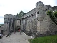 A colour photograph of the wall and a gate of an imposing late Medieval stone castle