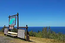 There are wooden information signs in the foreground, left and Lake Superior in the distance beyond the top of Brockway Mountain.