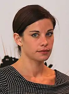 A woman with brown hair and a black dress with white dots on it.