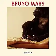 A gorilla sitting in a bed in the top of the sheets with a woman's legs lying next to him, the word "Gorilla" with capital font can be seen on the bottom of the picture, while the words "Bruno Mars" in red capital font are on the top of the image.