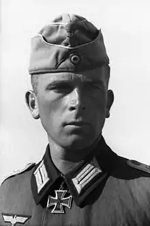 Black-and-white portrait of a man with a military uniform, side cap and an Iron Cross displayed at his neck.