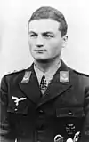 A man wearing a military uniform with an Iron Cross displayed at the front of his uniform collar.