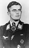 A man wearing a military uniform with an Iron Cross displayed at the front of his uniform collar.