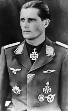 A man wearing a military uniform with various military decorations including an Iron Cross displayed at the front of his uniform collar.