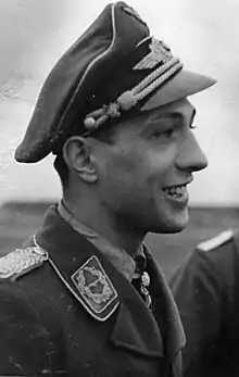 A man wearing a military uniform with a peaked cap on his head.