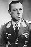 A man wearing a military uniform with various military decorations including an Iron Cross displayed at the front of his uniform collar.