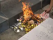 Paper yuanbao burned at a grave