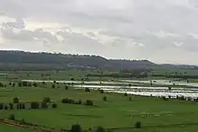 Water on grassy lowland with hills in the distance.