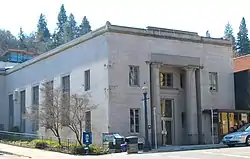 Photograph of a large building on a city street corner with the front entry flanked by two tall pillars