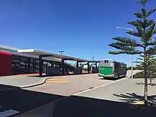 Bus at bus interchange with railway station in background