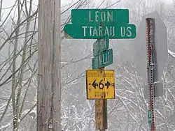 Example of a county route marker and fingerposts used by Cattaraugus County for its county routes prior to the late 1990s. The county now uses the standard pentagon; remaining older markers and fingerposts, including this New Albion example, have been left standing.