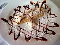 A cannoli with a chocolate sauce decoration