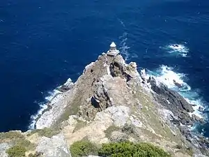 White surf breaks around Dias Rock, just offshore from the point