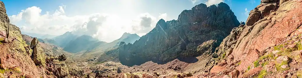 Panoramic photo of Capu Tafunatu (east face, in the shade) and the Col des Maures (Moorish Pass), above the Ciottulu a i Mori refuge in the upper Golo Valley. One can distinguish in the wall the turns of the normal access route leading to the "hole".