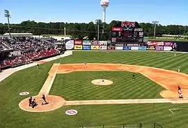 A green baseball field with a dirt infield on a clear, sunny day