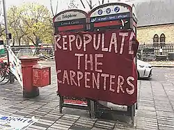 A red banner with white-lettered slogan tied across two phone boxes