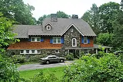 A dark brown wooden house with a projecting section of stone