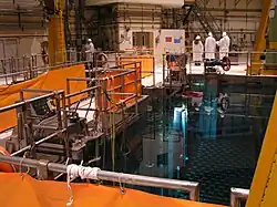 A group of people in radiation suits looking at a fuel pool