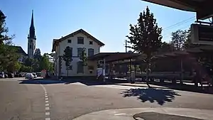 Three-story building with gabled roof and adjoining canopy-covered platforms