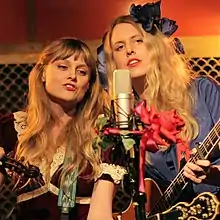 The Chapin Sisters share a microphone during a live performance