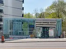 Photo of a small, glass-panelled subway station entrance under construction.