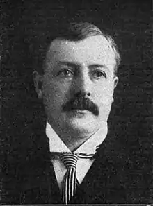 A black and white portrait photo of a man in a suit looking at the camera