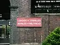 Distance board found in some disrepair on a station wall