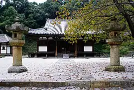 Wooden building with slightly raised floor, white walls and a hip-and-gable roof.