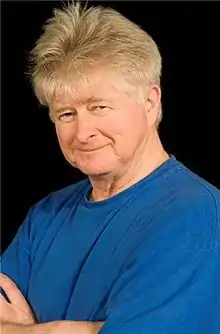 A man in a blue shirt in front of a black background