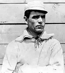 Clark Griffith standing against a wall and looking right, wearing a baseball uniform