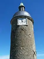 A circular Medieval stone tower with a clock near the top