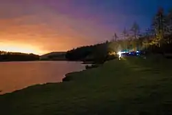 A lake surrounded by trees and fields at sunrise