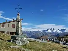 A view from the summit of a mountain with a cross monument on the left